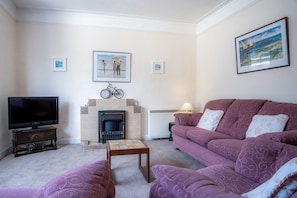 A living room with a television, a fireplace, a sofa, and a coffee table.