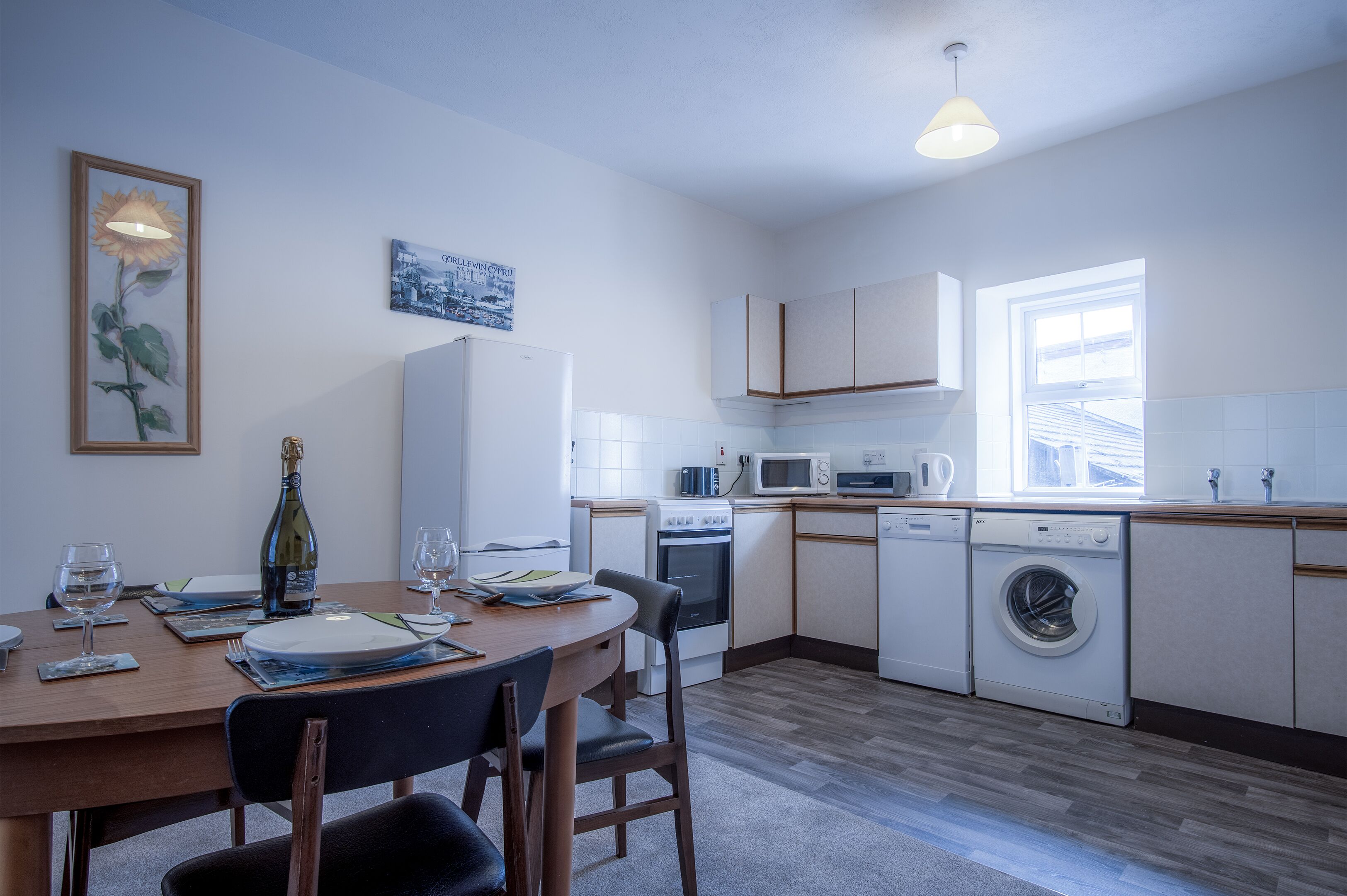 A compact kitchen with a dining area, white appliances, and a window providing natural light.