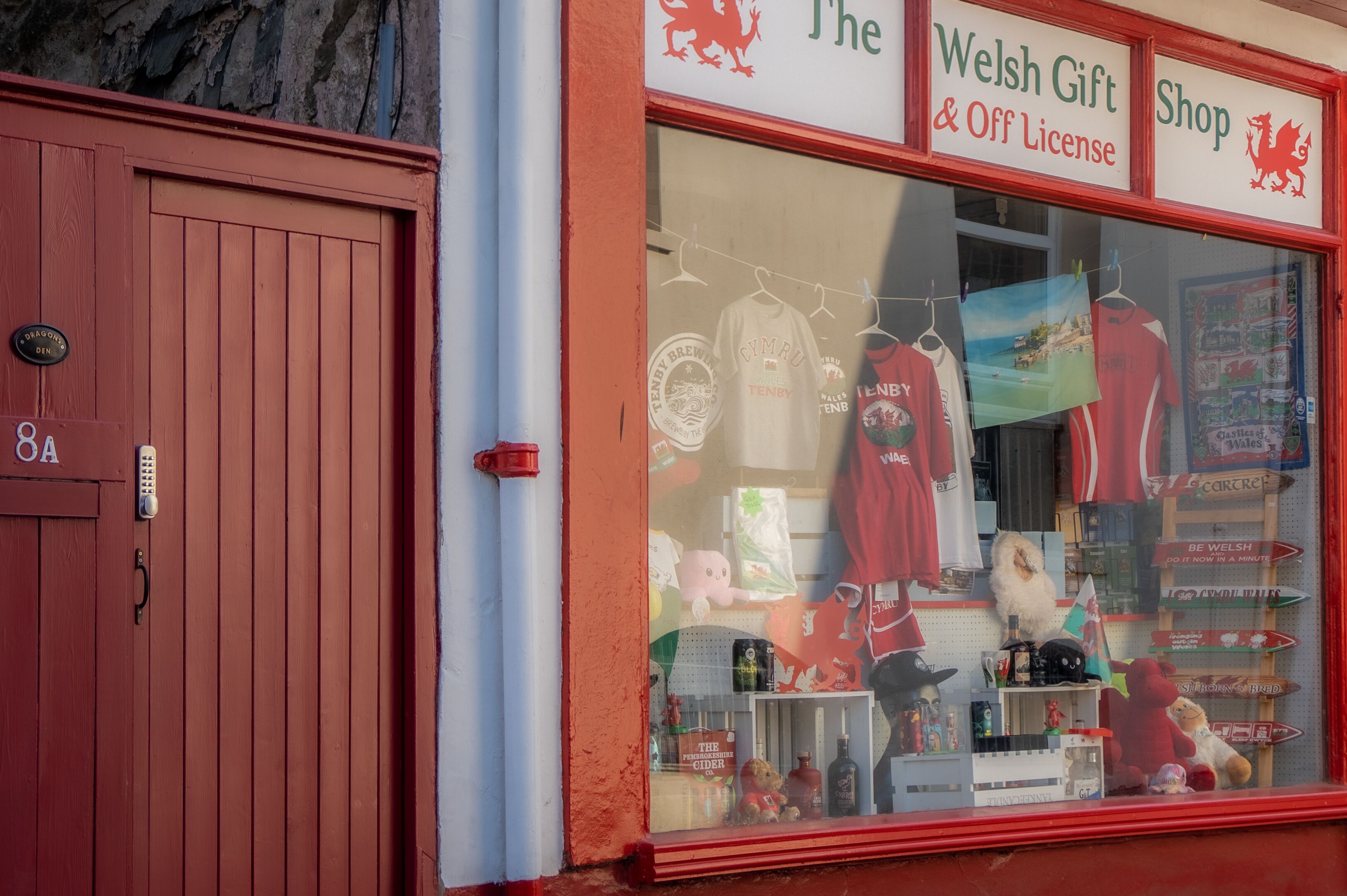 A storefront with a red exterior and a large window displaying Welsh-themed merchandise.
