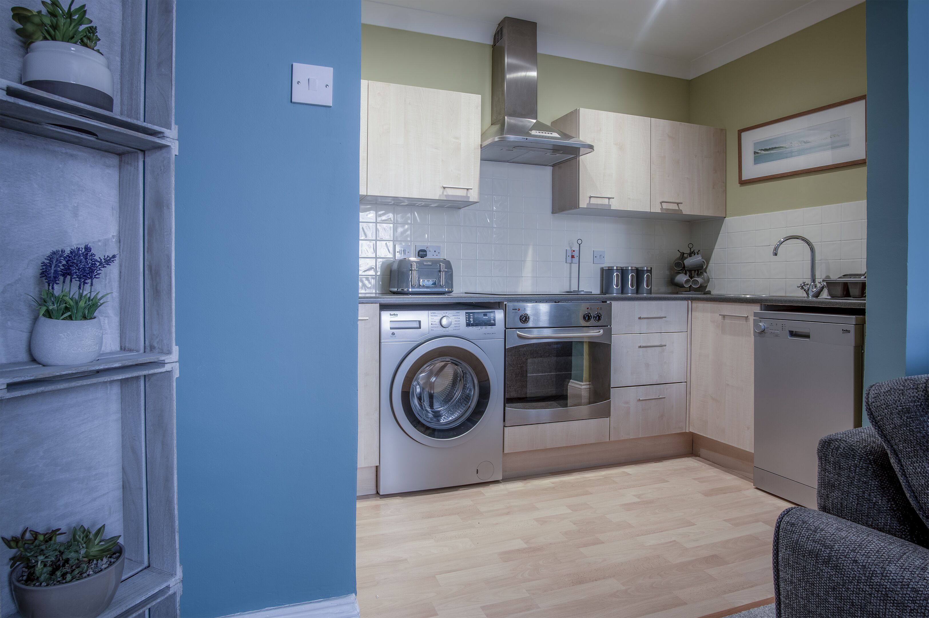 A modern kitchen with a washing machine, oven, and sink.