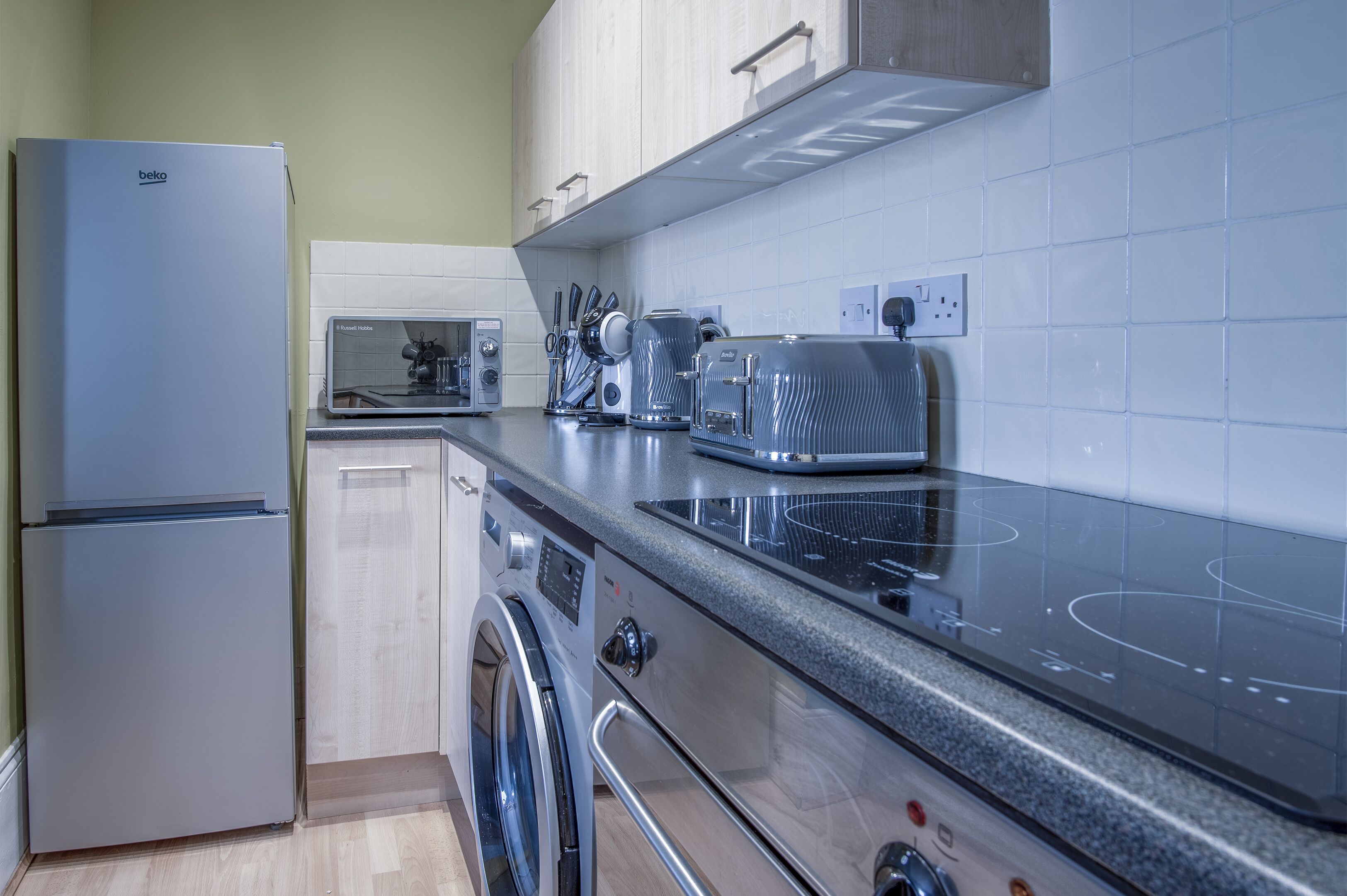 A modern kitchen with a built-in oven, microwave, and a washing machine.