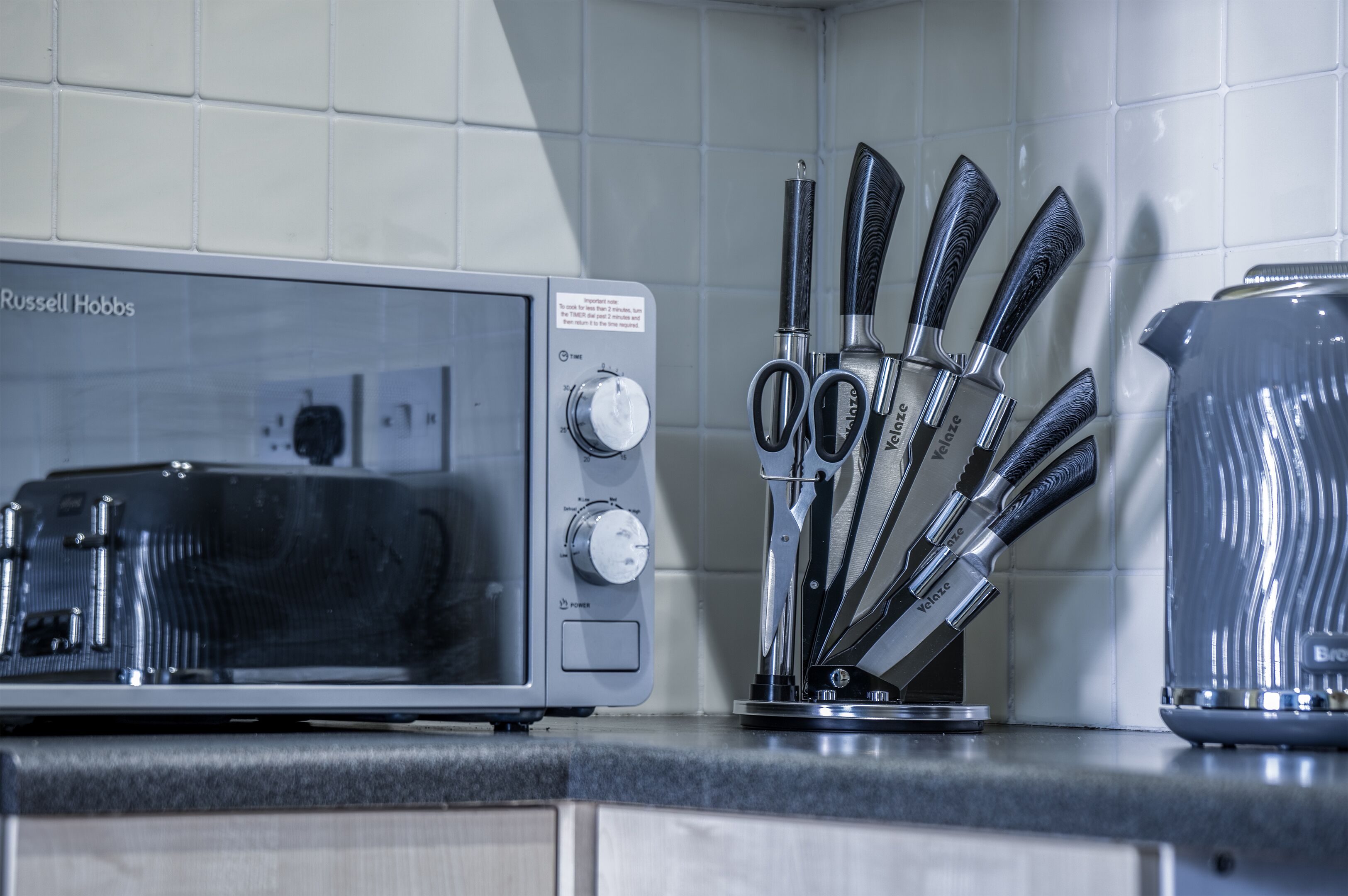 A kitchen with a microwave, a coffee maker, and a knife set on the counter.