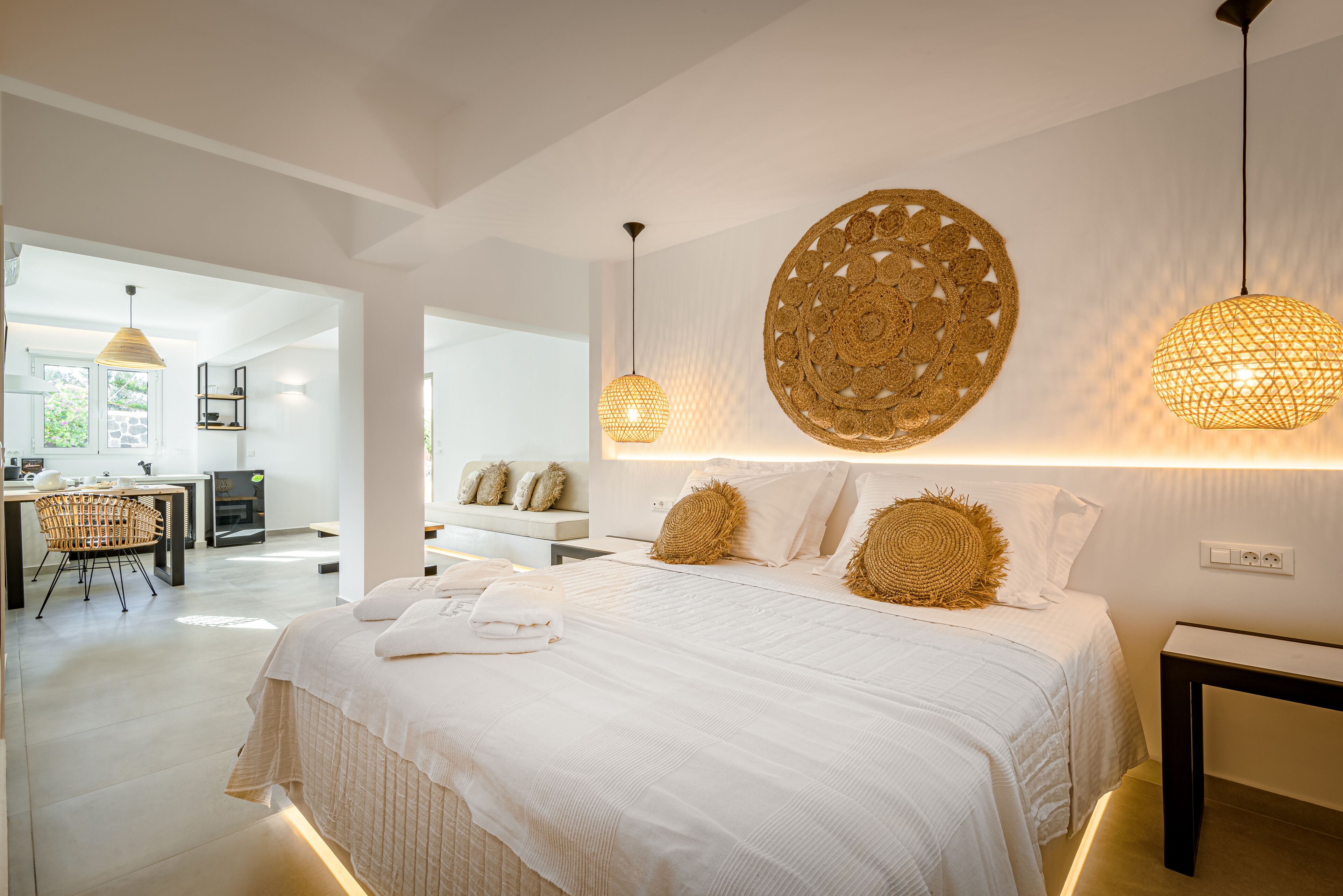 A modern bedroom with a large bed, two pendant lights, and a decorative wall piece.