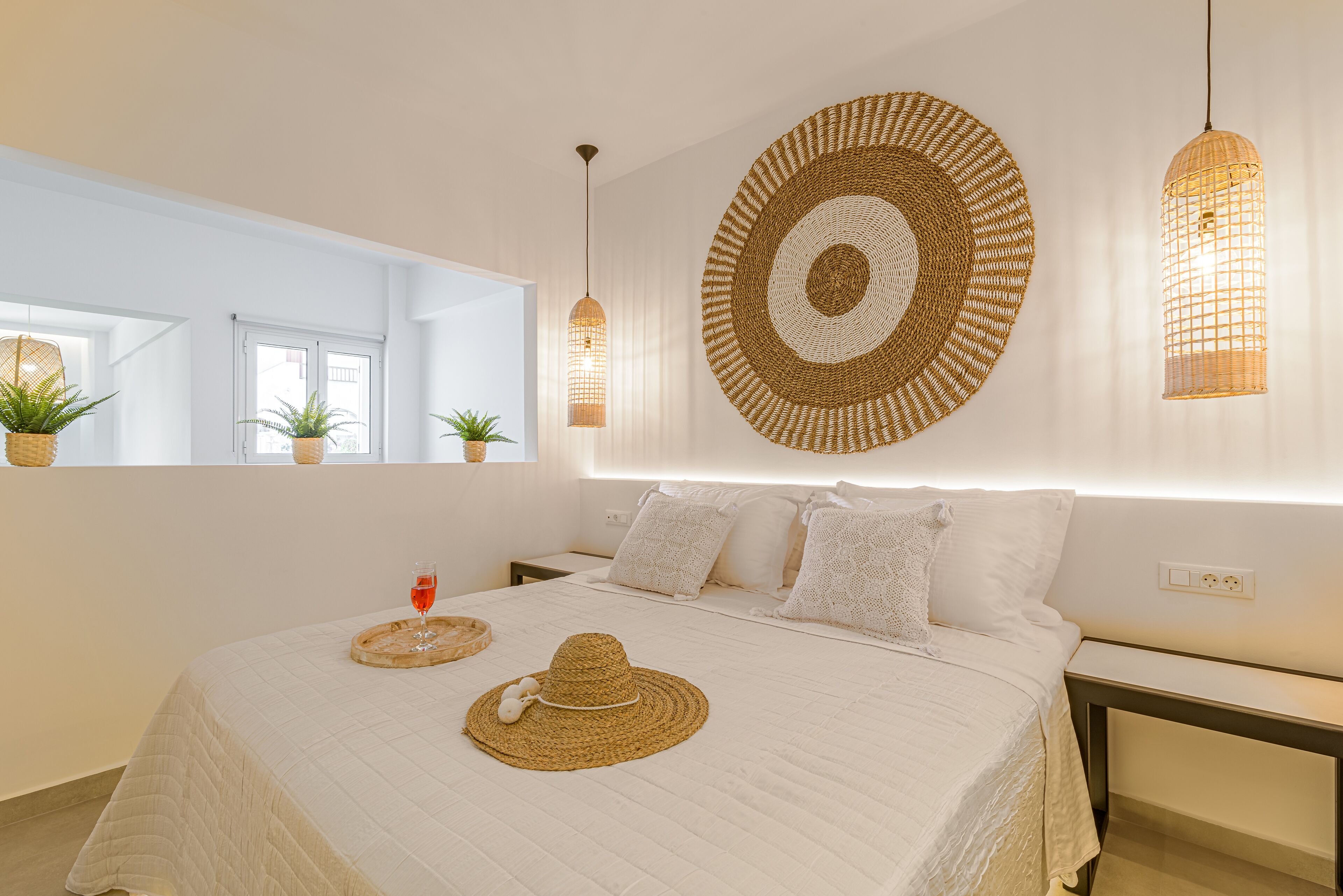 A bedroom with a large bed, a round woven wall art piece, and two hanging light fixtures.