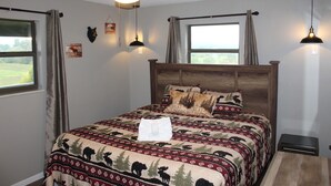 Ein Schlafzimmer mit einem großen Bett, einem Deckenventilator, zwei Fenstern mit Vorhängen und Wandleuchten.