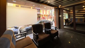 A hotel lobby with a large glass window, seating area, and a striped ceiling. - Hotel InTourist by Agira Hotel (Bengaluru)