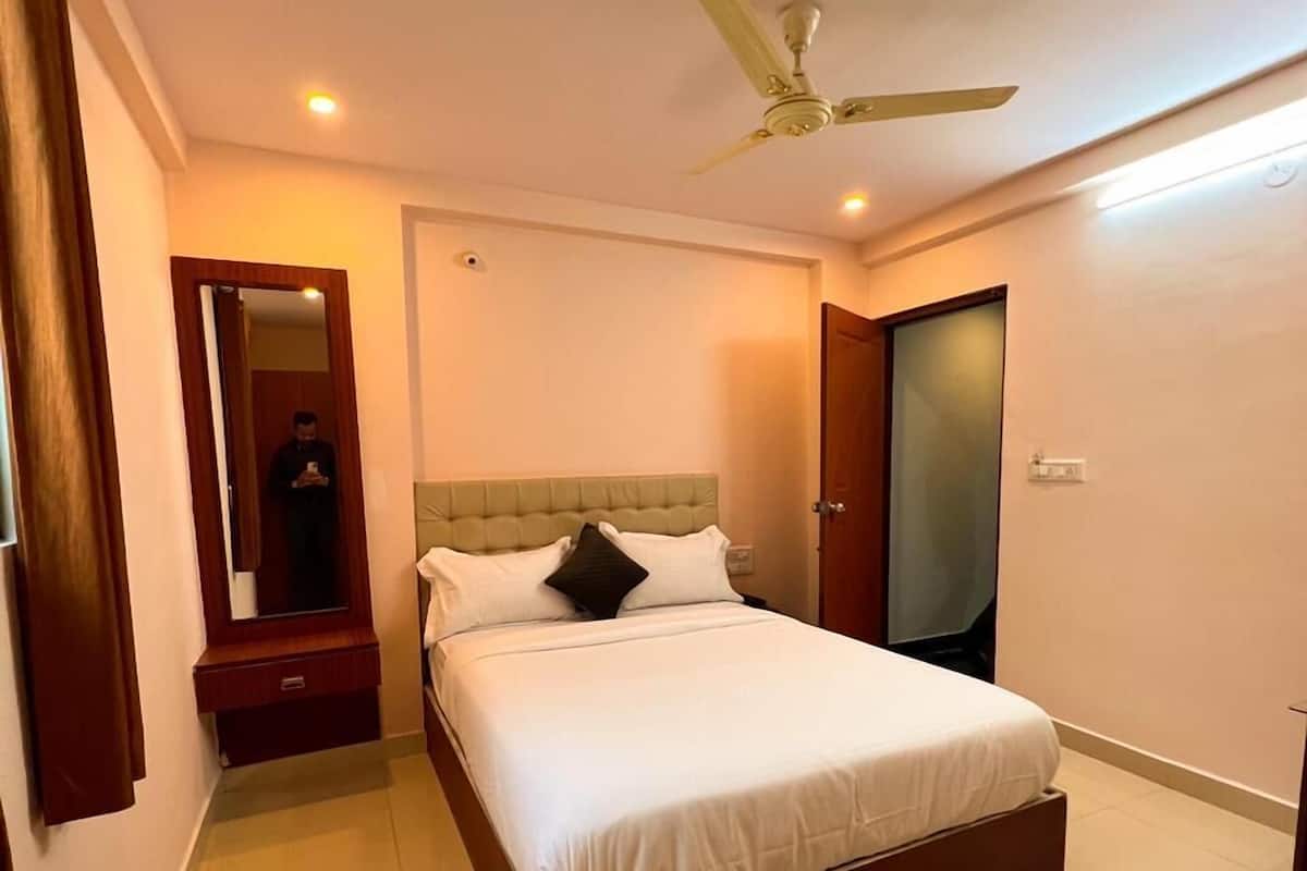 A bedroom with a bed, a ceiling fan, a nightstand, a mirror, and a door.
