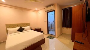A modern hotel room with a bed, bedside table, and a TV. - Hotel InTourist by Agira Hotel (Bengaluru)