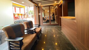 A hotel lobby with a reception desk, seating area with sofas and tables, and a view of the street outside. - Hotel InTourist by Agira Hotel (Bengaluru)