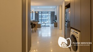 Een modern appartement met een zithoek, eethoek en een wasmachine.