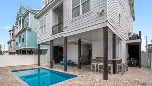 Een woonhuis met een zwembad, terras en een overdekte patio.