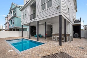 A residential property with a swimming pool, outdoor seating, and a covered patio area. - Luxury boulevard home w/private pool, outdoor kitchen-absolute heaven! (North Myrtle Beach)