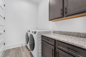 A laundry room with a washing machine, a countertop, and cabinets.