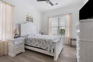 Un dormitorio con cama, mesitas de noche, cómoda y ventilador de techo.