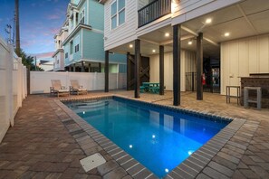 A swimming pool with a tiled edge, surrounded by a brick patio.