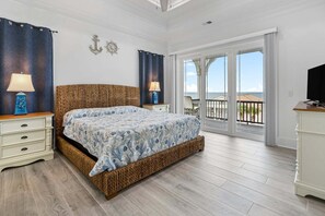 A bedroom with a bed, nightstands, a television, and a balcony with a view.