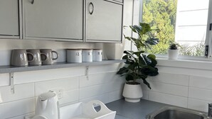 Una cocina moderna con armarios grises, un lavamanos de acero inoxidable y una ventana con persianas.