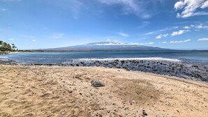 A beach with a mountain in the distance, clear skies, and calm waters. - Stunning Direct Oceanfront home on the beach, AC, pool, spa (Wailuku)