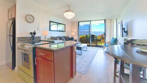 A modern kitchen with a central island, a dining area with a table, and a living room with a sofa. - Stunning Direct Oceanfront home on the beach, AC, pool, spa (Wailuku)