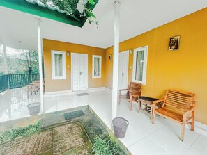 A spacious balcony with a tiled floor, two wooden benches, and a small water feature. - Rinjani Garden Syariah by ecommerceloka (Sembalun Lawang)
