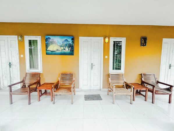A waiting area with wooden chairs and a painting of a tent on the wall. - Rinjani Garden Syariah by ecommerceloka (Sembalun Lawang)