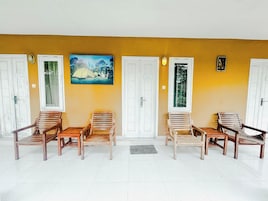 A waiting area with wooden chairs and a painting of a tent on the wall.
