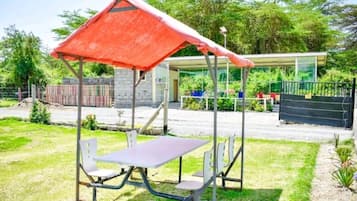 An outdoor seating area with a table and chairs under a red canopy.