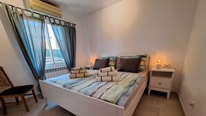 Une chambre à coucher avec un lit, des tables de chevet, une chaise et une fenêtre avec des rideaux.