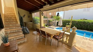 Une terrasse couverte avec une piscine, des marches en pierre et une table avec des chaises.