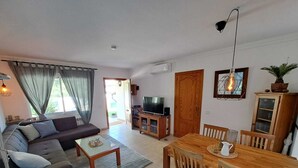 Un salon comprenant un canapé, une table basse, un meuble pour la télévision, une table à manger en bois et des chaises.