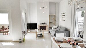 A modern living room with a TV, sofa, and dining area set up for a meal. - Adhilli i residence (Rethymno)