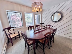 A dining area with a wooden table, six chairs, and a decorative mirror on the wall. - Park Place Aspen Condo • Walk to Main St. • Snowflake Lift • Pool+Hot Tubs (Breckenridge)