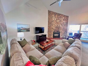 A living room with a stone fireplace, a flat-screen TV, a sofa, and a coffee table.