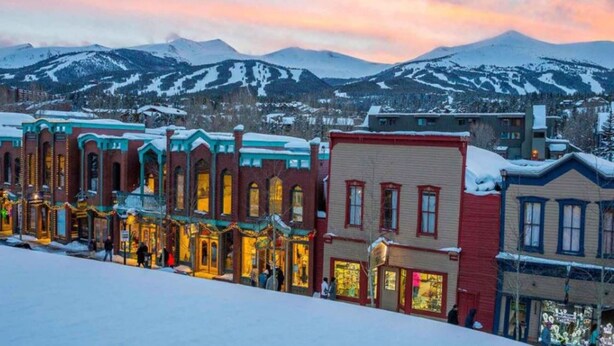 A row of historic buildings with large windows and a snow-covered street.
