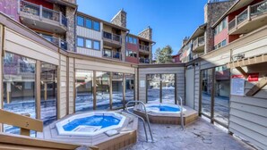 A spa area with two hot tubs and a wooden deck.