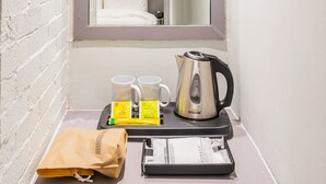A compact bathroom with a white sink, a mirror above it, a small window, and a white refrigerator below. - Lenith Hotel Seomyeon (Busan)