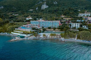 Un hotel frente al mar con varios pisos, una piscina y una zona de playa.