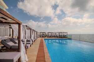 Un área junto a la piscina con tumbonas y una terraza de madera.