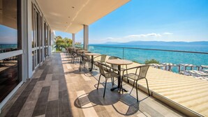 Un balcón con mobiliario exterior, vista al mar y fachada de edificio moderno.