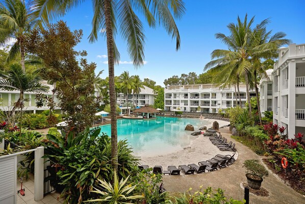 Relax by the resort's central pool surrounded by a sandy beach area and lush tropical gardens.