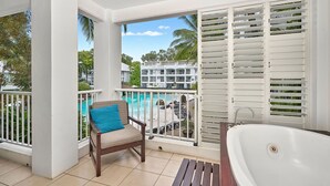 A balcony with a view of a pool and a building in the background. - Whispering Palms Beach Club Spa Suite (Palm Cove)