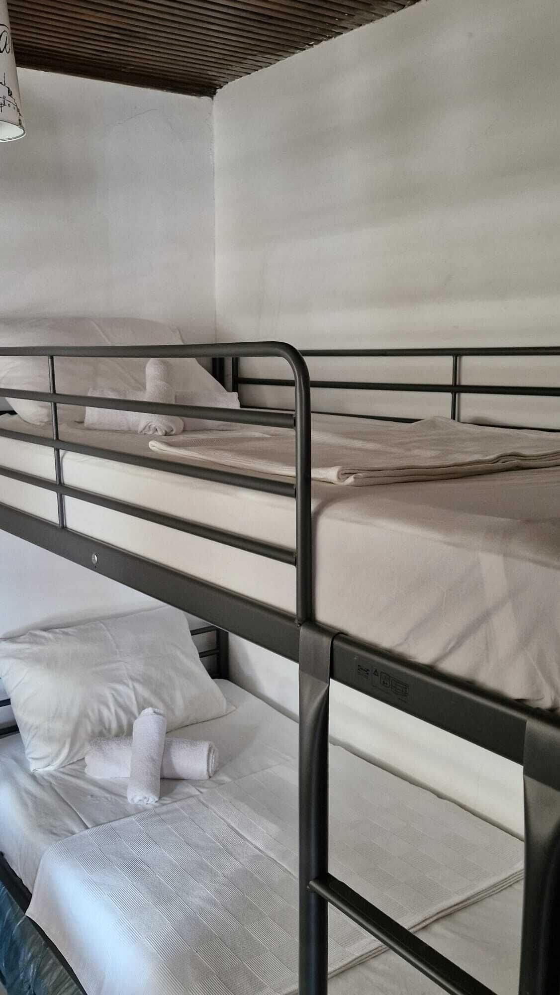 A bunk bed with a metal frame, white bedding, and a pillow.