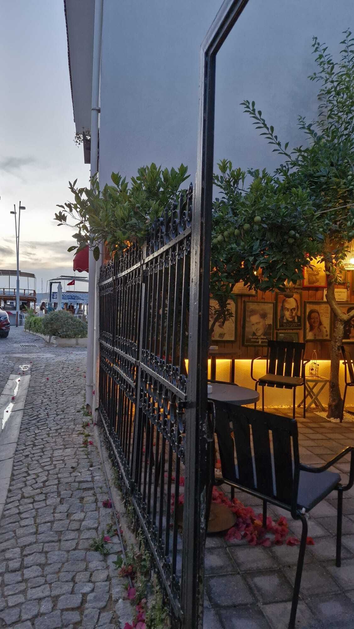 A cobblestone path, a metal fence, and outdoor seating with chairs and tables.