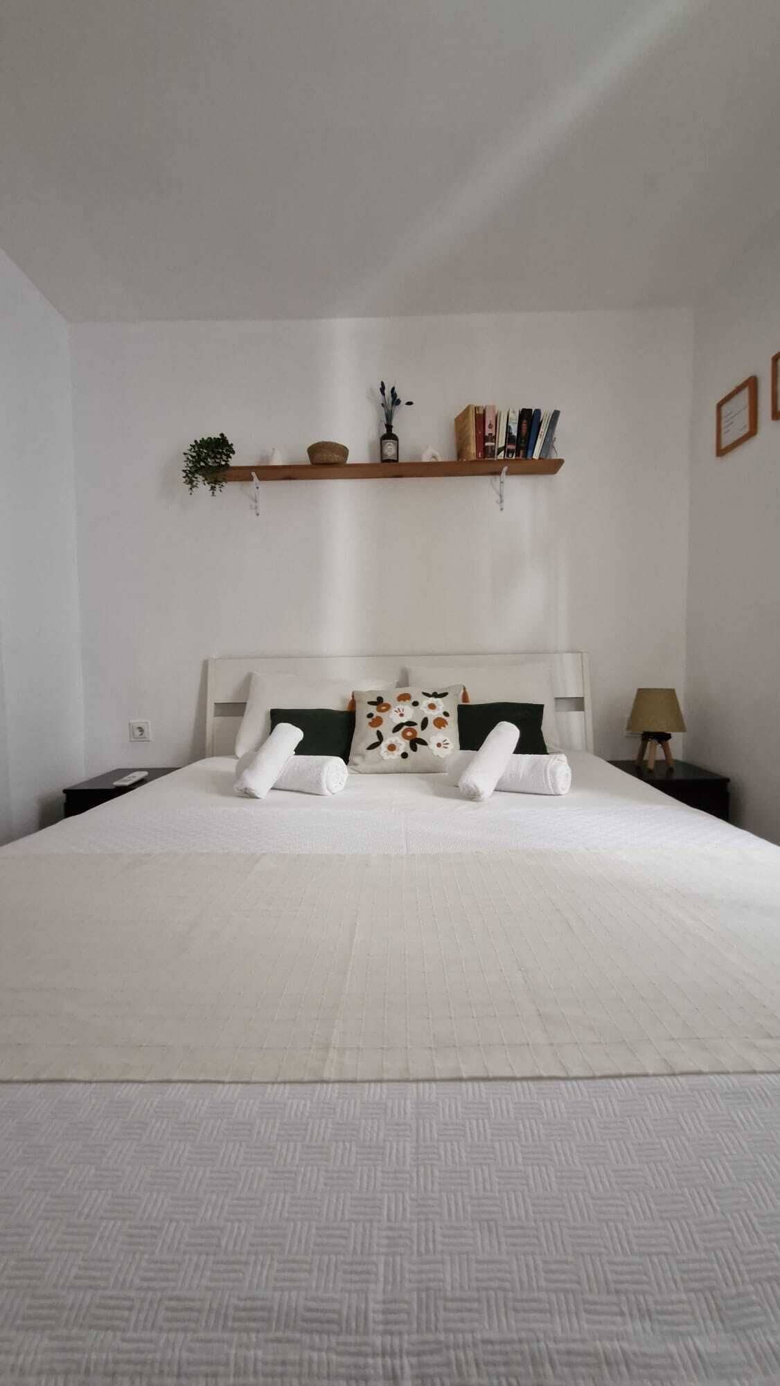 A neatly made bed with white linens, a headboard, and decorative pillows.