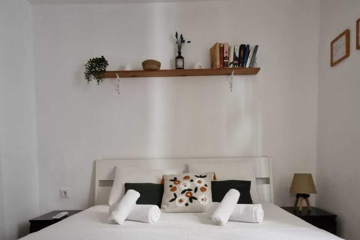 Un lit bien fait, avec des draps blancs, une tête de lit et des coussins décoratifs.