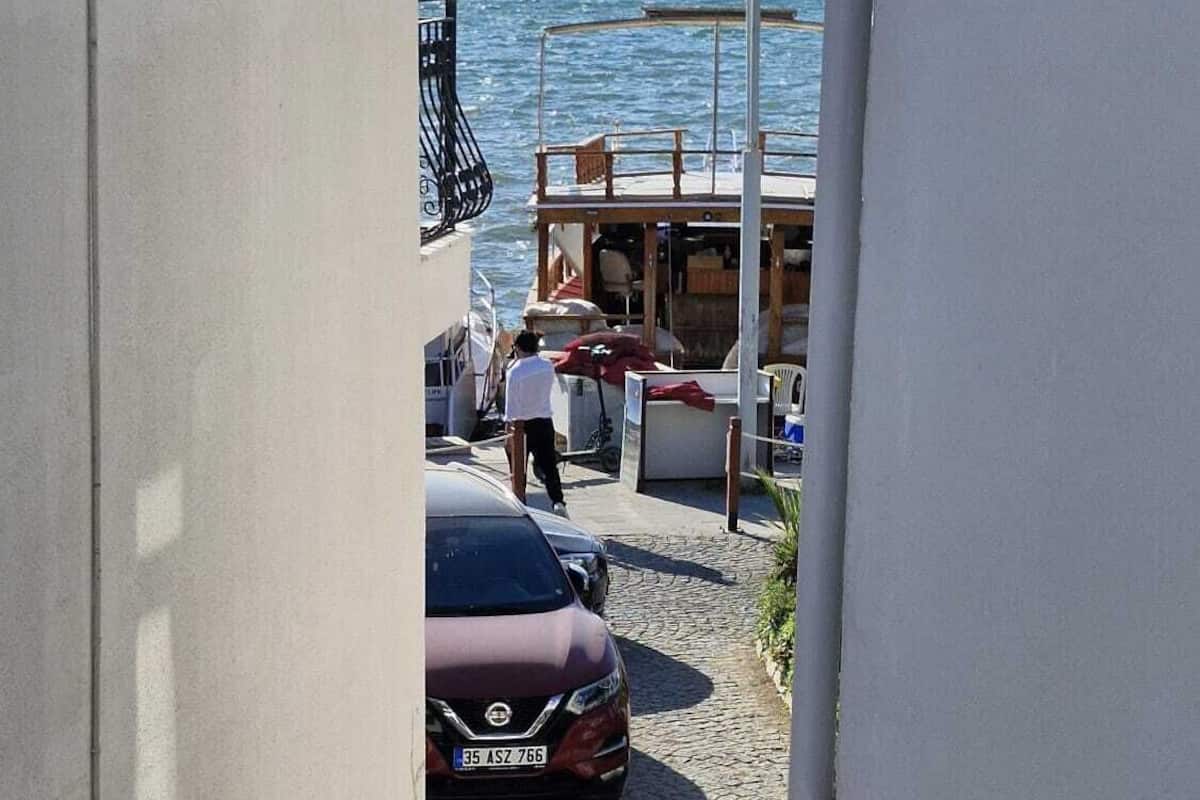 Une rue étroite, avec une voiture garée et un immeuble doté d’un balcon surplombant une étendue d’eau.