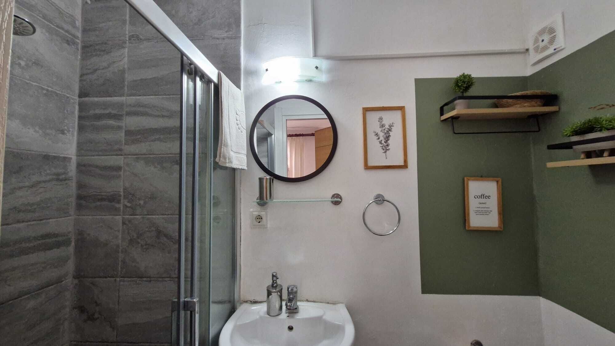 Ein Badezimmer mit Duschkabine aus Glas, einem Waschbecken mit Spiegel und gerahmten Bildern an der Wand.