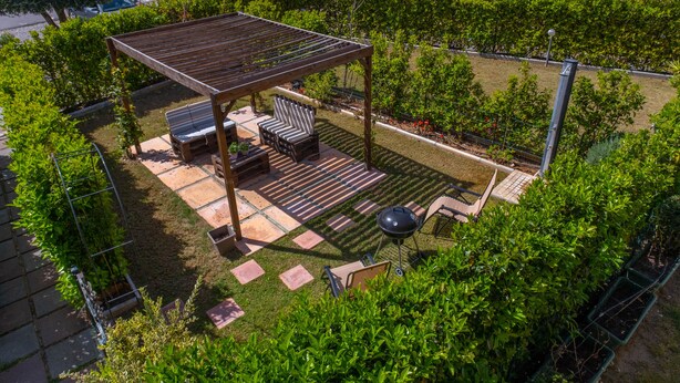Ein Dachgarten mit einer Pergola, Sitzgelegenheiten im Freien und einem Grillbereich.