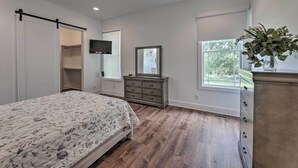 Een slaapkamer met een bed, een dressoir, een televisie en een raam met uitzicht.