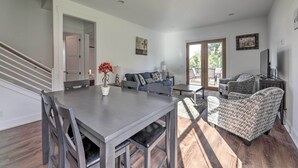 Een ruime woonkamer met een eettafel, banken en gestreept fauteuils. Een trap leidt naar een andere kamer.